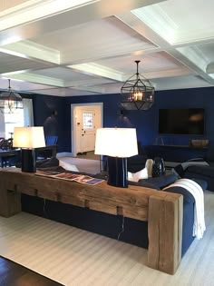 a living room filled with furniture and two lamps on top of a wooden table in front of a blue wall