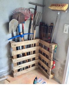 a wooden crate filled with gardening utensils on top of a tiled floor next to a wall