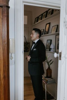 a man in a tuxedo is looking out the door to his living room