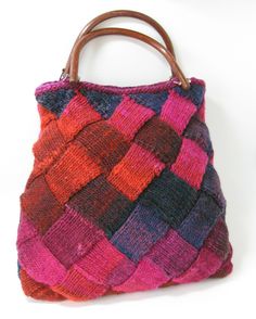 a handbag made out of knitted material on a white surface with a wooden handle