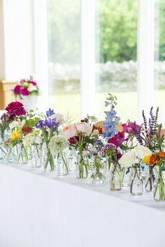 there are many vases with flowers in them on the table next to each other