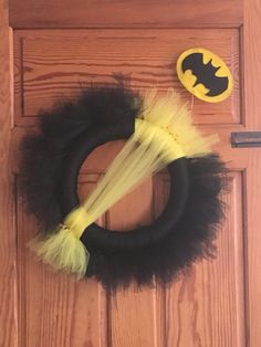 a black and yellow wreath with a bat on it next to a batman pinata