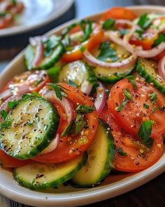 a white plate topped with sliced cucumbers and tomatoes