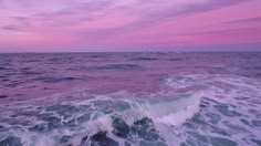 the ocean is full of waves and pink clouds