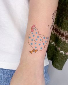 a woman with a tattoo on her arm that has a blue and white polka dot chicken on it