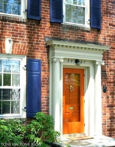 a red brick house with blue shutters and a yellow door