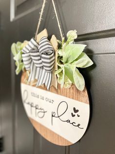 a wooden sign hanging from the side of a door with a bow on it that says welcome to our place