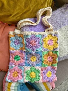 a crocheted purse sitting on top of a bed next to pillows and blankets