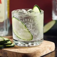 cucumber slices are placed on the edge of a glass that is sitting on a cutting board