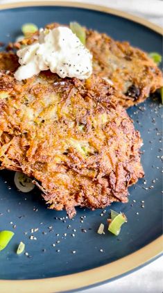 two crab cakes on a blue plate with sour cream and green onion garnish