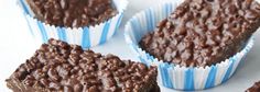 four chocolate cupcakes sitting on top of a white plate with blue and white paper wrappers