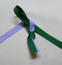 a purple and green ribbon on a white surface