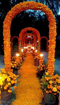 an archway decorated with orange flowers and lit candles for a wedding ceremony in the evening