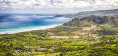 an aerial view of the ocean, mountains and beach from a high point on a cloudy day