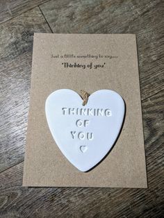 a white heart shaped ornament with the words thinking of you on it