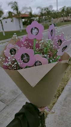 a person holding a bouquet of flowers on the side of the road with pictures attached to it