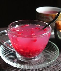 a glass cup filled with pink liquid next to other cups