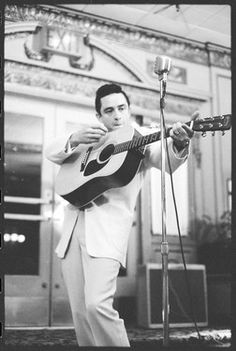 a man holding a guitar while standing next to a microphone