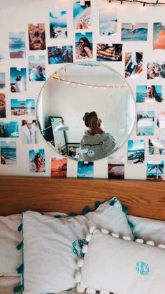 a bed with white pillows and pictures on the wall behind it, along with a round mirror