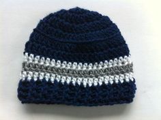 a crocheted blue hat with white and gray stripes on it sitting on top of a table