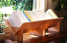 an open book is sitting on top of a wooden stand in front of a window