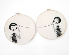 two embroidery hoops with an image of a woman pulling a man's hair