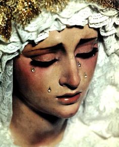 a close up of a woman's face with gold and white decorations on her head