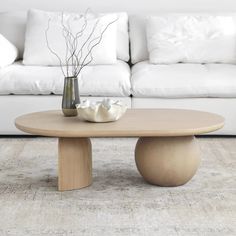 a white couch sitting next to a wooden table on top of a carpeted floor