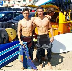 two men standing next to each other in front of surfboards