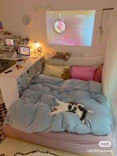 a cat laying on top of a bed in a room with a projector screen