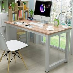 a desk with a computer on it in front of a window and bookshelf