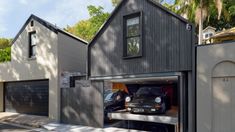 two cars are parked in an open garage door on the side of a house that's surrounded by palm trees