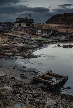 an old boat sitting on top of a rocky shore next to a body of water