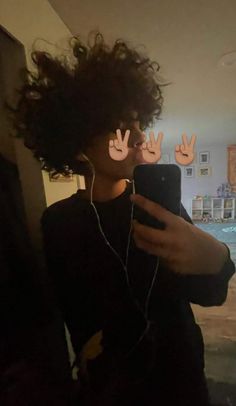 a person with headphones on taking a selfie in front of a mirror that has hands drawn on it