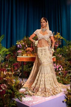 "Unveil Eternal Elegance - Our All Ivory Bridal Lehenga Set is a vision of grace and allure. Soft pink crystals and shimmering gold metals create a celestial beauty. Our signature ivory blouse with tassels adds a modern touch, while a soft ivory tulle head veil completes the enchantment. Step into the spotlight with this captivating ensemble, making your special day truly unforgettable." Colour: Ivory Fabric: Tulle / Fluid / Organza Technique: Hand Embroidery, Patchwork No of set: 3 Delivery Tim Glamorous Gold Hand-embellished Sets, Glamorous Gold Choli With Intricate Embroidery, Glamorous Gold Lehenga With Sheer Dupatta, Glamorous Gold Sharara For Wedding, Glamorous Gold Wedding Sharara, Glamorous Gold Sets For Festivals, Glamorous Gold Choli With Sheer Dupatta, Glamorous Gold Sharara For Festivals, Hand Embellished Traditional Drape Set For Ceremony