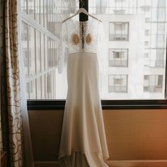 a wedding dress hanging in front of a window