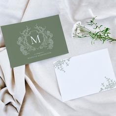 the wedding stationery is laid out on top of the bed with white flowers and greenery