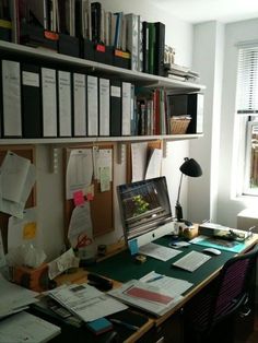 a desk with a laptop computer sitting on top of it next to a bookshelf