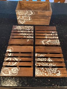 four wooden boxes sitting on top of a table with white designs painted on the lids