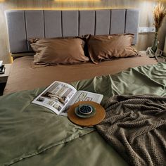 a bed with two pillows and an open magazine on top of it, next to a night stand