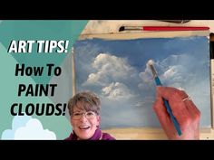 a woman holding a paintbrush in front of a painting with the words art tips how to paint clouds