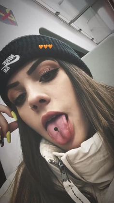 a woman sticking her tongue out while wearing a hat