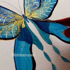 someone is painting a butterfly with blue and yellow paint on it's wings,