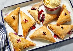 several pastries on a tray with ice cream in a bowl and spoons next to them