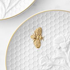 two white and gold plates with bees on them