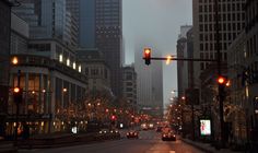 a city street with traffic lights and buildings in the background at night, as seen from across the street