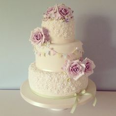 a three tiered wedding cake with purple flowers on top