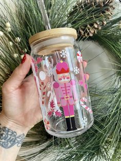 a hand holding up a glass jar with a nutcracker design on the lid