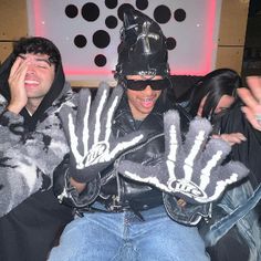 two men dressed in costumes sitting on a couch with their hands up to the camera