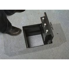 a person standing next to a metal box on the ground with holes in it and their feet visible